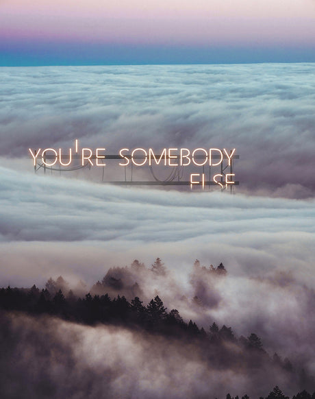 YOU'RE SOMEBODY ELSE: A neon sign reading Youre Somebody Else stands above a layer of clouds at sunset. The sign is illuminated by the setting sun, casting a warm glow on the clouds below. The sign appears to be a large structure, possibly a billboard or a sign on a building. The clouds are thick and white, and the sun is setting behind them, creating a beautiful, ethereal scene.