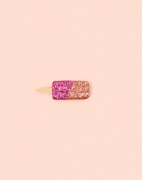 GLITTER ICE CREAM PINK: A single popsicle with a pink and gold glitter coating is photographed on a pastel pink background. The popsicle is facing the camera with its wooden stick visible.