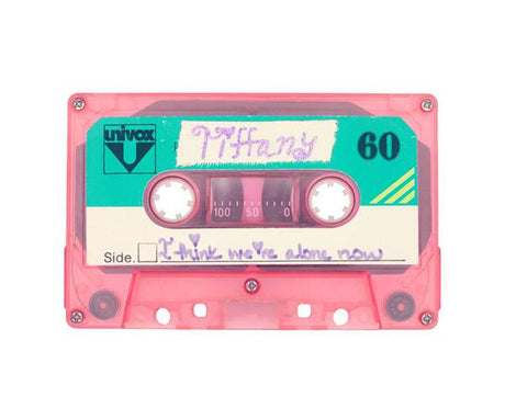 I THINK WE'RE ALONE NOW: This image shows a pink cassette tape with a handwritten label that reads Tiffany and 60. The label is on a teal background. The cassette tape has a clear plastic shell and is in good condition. The tape is likely from the 1980s or 1990s.