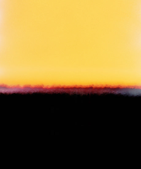 GIANNA: A photograph of a golden hour sunset over a silhouette landscape. The image features a vibrant, yellow sky with a thin band of orange and purple at the horizon. The foreground is a dark silhouette of trees and hills.