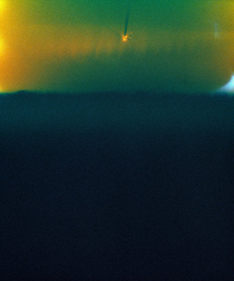 APPALACHIA DREAM: A faded, grainy photograph of a distant comet in the early morning sky. The image is in low resolution, with a dark, blurred background and a small, bright comet in the upper portion of the frame. The sky above the comet is a faint yellow and green, with a slight orange glow.