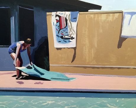 CONCRETE BEACH: A woman in a swimsuit is bending over to fold a large blue towel near a swimming pool. The pool is in the foreground, and the woman is standing on a pink deck. There is a fence behind her with a brightly colored painting hanging on it. The sun is shining brightly.