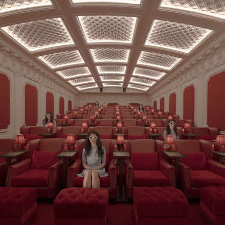 NIGHT AT THE MOVIES: A woman wearing 3D glasses sits in a plush, red velvet seat in a grand movie theater. She is surrounded by other audience members, all seated in similar red velvet chairs, enjoying a movie screening. The theater has a luxurious and old-fashioned ambiance with ornate details and a patterned ceiling.