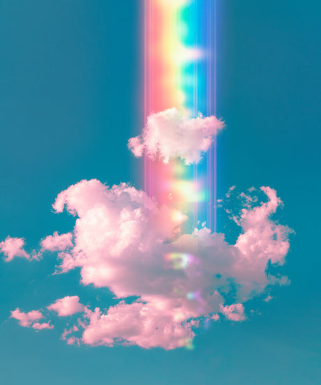 THE YOUNGEST STARS: A vibrant rainbow shines through fluffy white clouds in a bright blue sky. The image captures a beautiful, ethereal moment in nature, with the rainbows light illuminating the clouds and creating a sense of wonder.