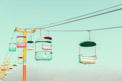 SANTA CRUZ AMUSEMENT PARK: A row of colorful gondolas travel along a cable system against a clear blue sky. The gondolas are suspended from a yellow pole with multiple cables strung between them. This image captures the excitement of a day at the amusement park.