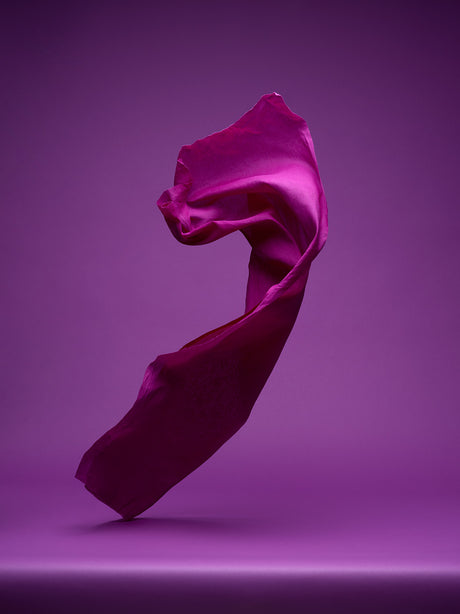 DANCING FABRIC, VIOLET: A single piece of purple fabric is floating in the air against a purple background. The fabric is in motion, creating a sense of movement and energy. The image is simple yet elegant, capturing the beauty of a basic material.