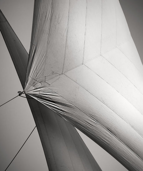 SAILS III COTE D'AZUR: A close-up view of a sailboats sail, showcasing its textured surface and intricate lines. The photograph is in black and white, highlighting the dramatic contrast of the sail against the sky.