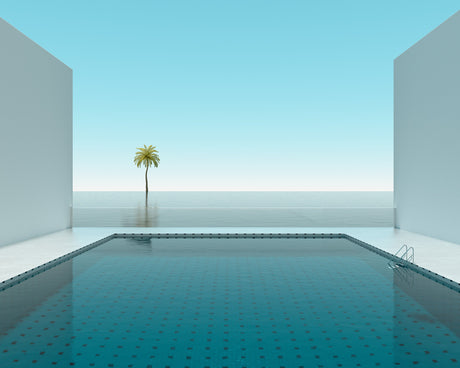 POOL PALM TREE: This image features a modern minimalist pool deck with a single palm tree growing in the distance. The pool appears to be seamlessly connected to the ocean in the background, creating a sense of serenity and tranquility.