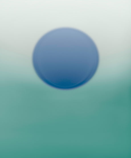 ENDLESS SUMMER NO16: A single blue circle hangs in the center of a blurry, multi-colored background. The colors in the background are green and white, fading to a darker green at the bottom of the image. The blue circle is slightly out of focus, giving the image a soft, ethereal quality.