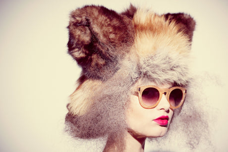 FOX: This image shows a woman with curly hair wearing a large fur hat. She is wearing sunglasses, and her lips are painted a bright red.