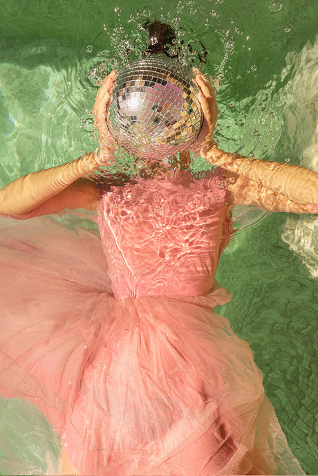 LIGHT UP: A woman wearing a pink dress is floating in the water. Her dress billows around her as she relaxes on the surface of the water.