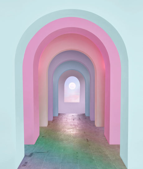 MOONBEAM: A hallway lined with pastel-colored arches leads to a window with a bright blue sky and a white sun visible through the glass. The archway is made of multiple layers of pale pink, blue, and purple hues. The floor is made of tiles with a slight greenish tint.