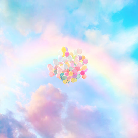 OVER THE RAINBOW: A cluster of colorful balloons floats upwards against a backdrop of pastel-colored clouds. The balloons are various shades of pink, blue, yellow, and green, and they are arranged in a loose cluster. The sky is a soft blue with hints of pink and purple, creating a dreamy and whimsical atmosphere.