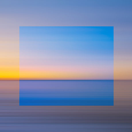 BLUE DAWN: A vibrant, blurred photograph of a sunset over a calm body of water. The colors of the sky blend into the ocean, creating a seamless, dreamy landscape. The soft, pastel tones of the sunset add a sense of tranquility to the image.