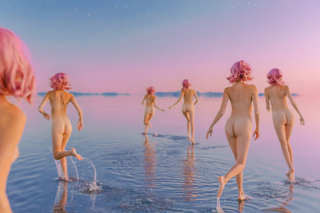 CROSSOVER DREAMS II: Several nude women are walking along the sandy shoreline of a beach, their figures silhouetted against the horizon. The women are confidently striding, with the ocean waves gently lapping at their feet.